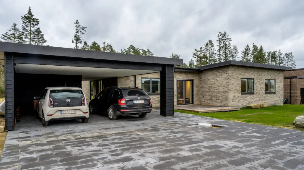 Moderne murstensvilla i Sejs med mørk carport og flisebelægning, opført af Murermester Preben Poulsen.