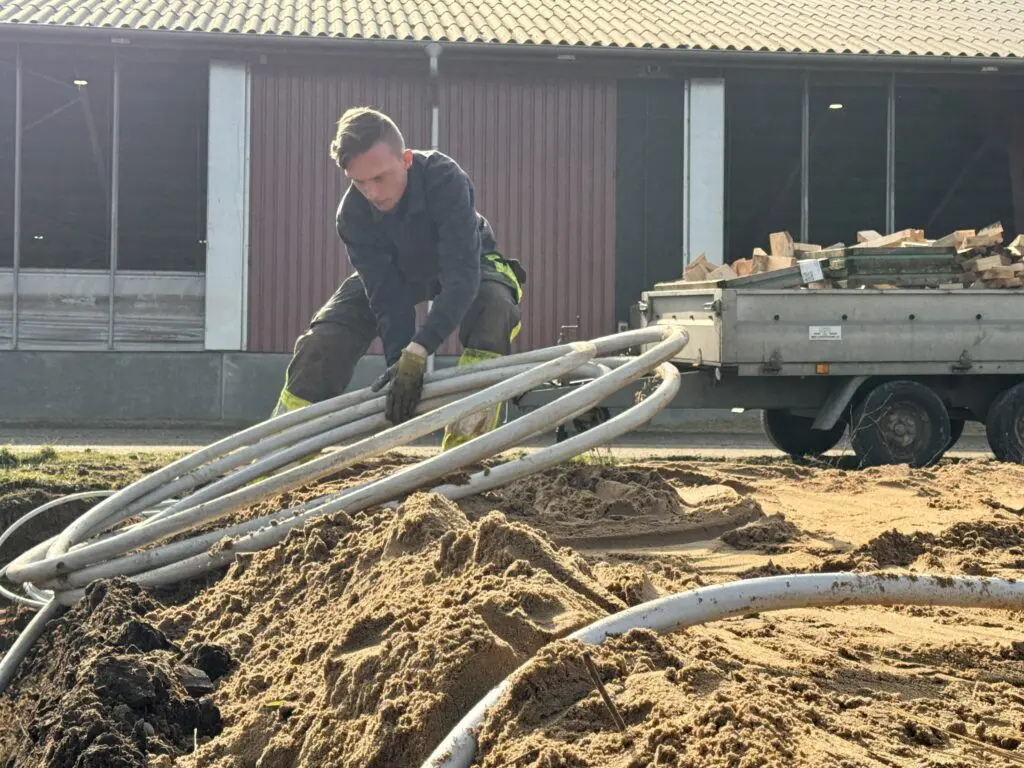Medarbejder hos Preben Poulsen udfører jordarbejde og håndterer rør til nyt byggeri eller energianlæg.