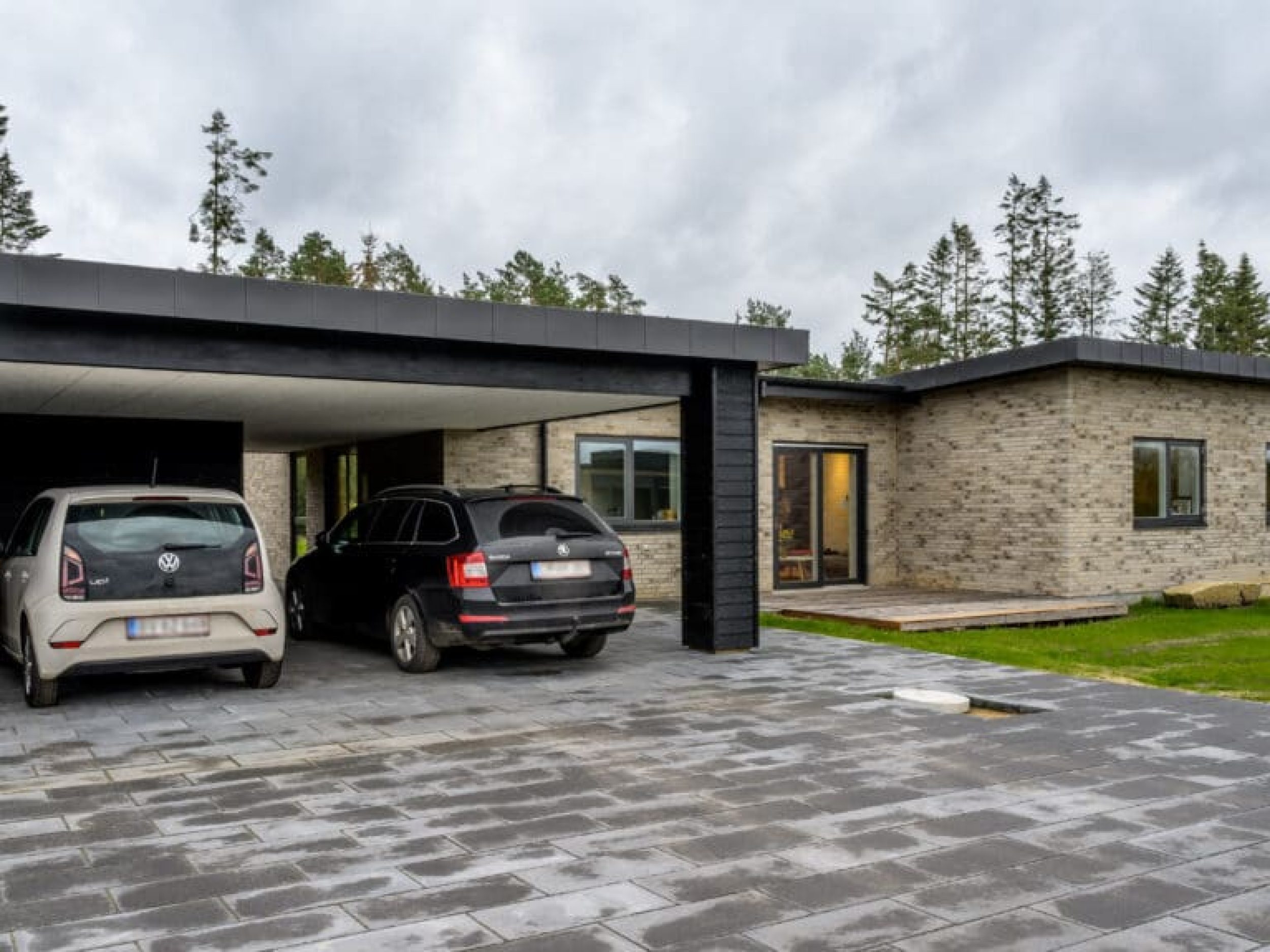 Moderne murstensvilla i Sejs med mørk carport og flisebelægning, opført af Murermester Preben Poulsen.